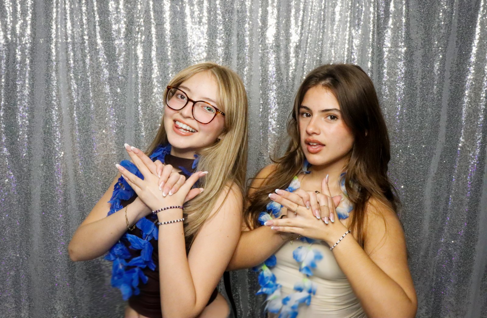 Two friends posing at a Kiko Booths photobooth with a silver sequin backdrop in Miami