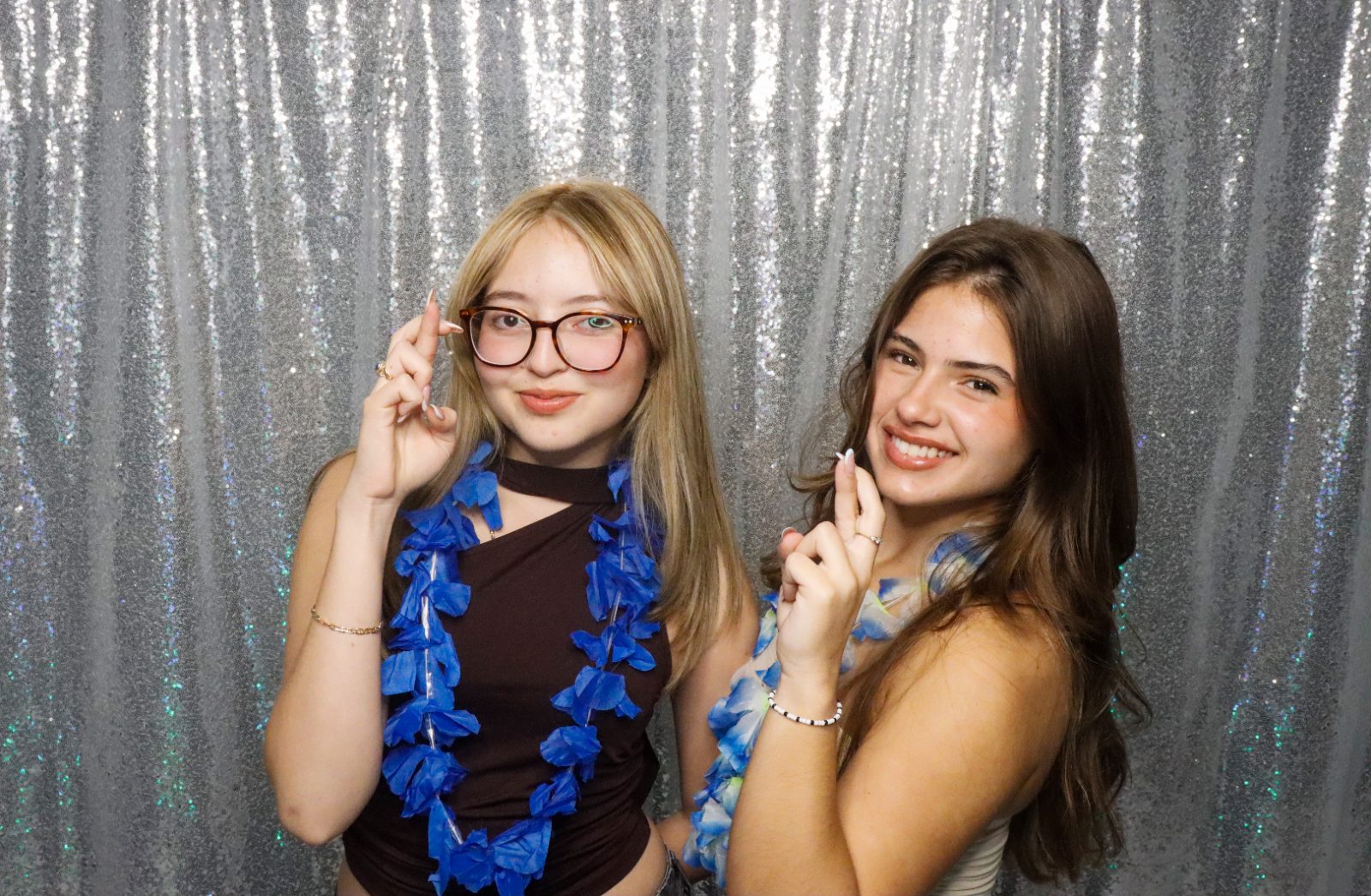 Two friends smiling at the ARO photobooth with a silver sequin backdrop