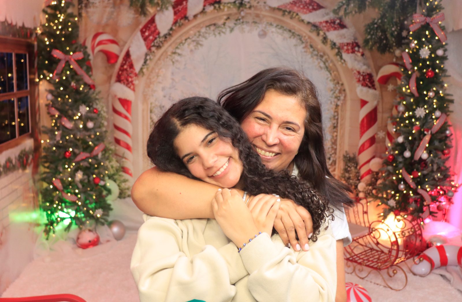 Mother and daughter smiling at a Christmas photobooth backdrop in Miami