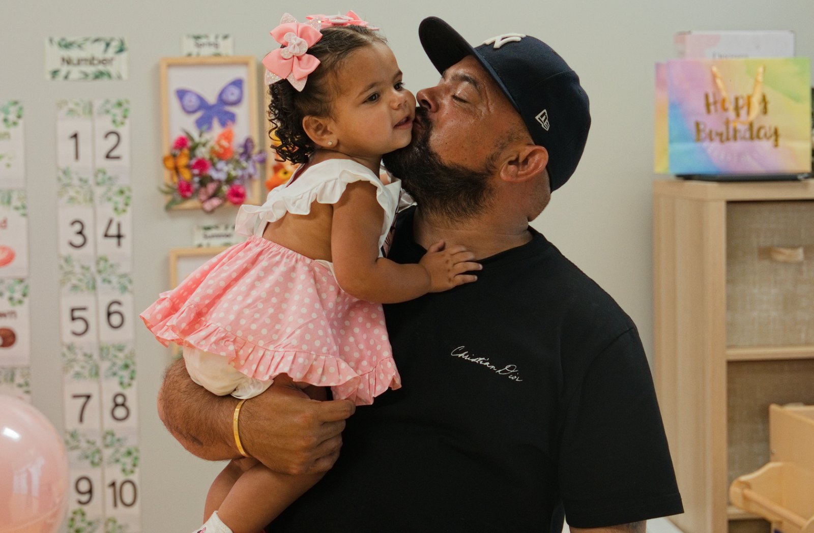 Father kissing his daughter on the cheek at her first birthday party in Miami