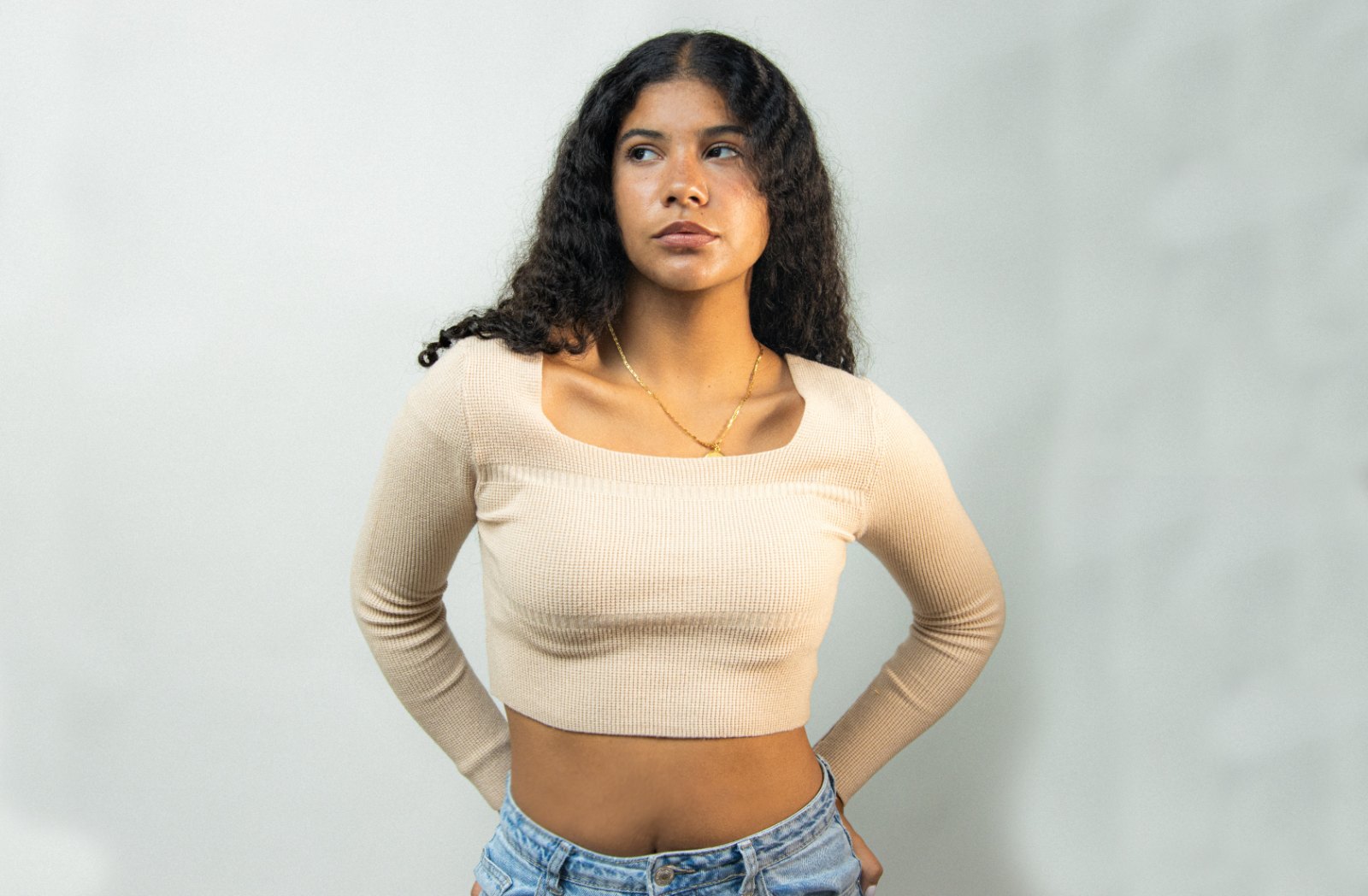 Portrait of a young woman with curly hair against a light backdrop